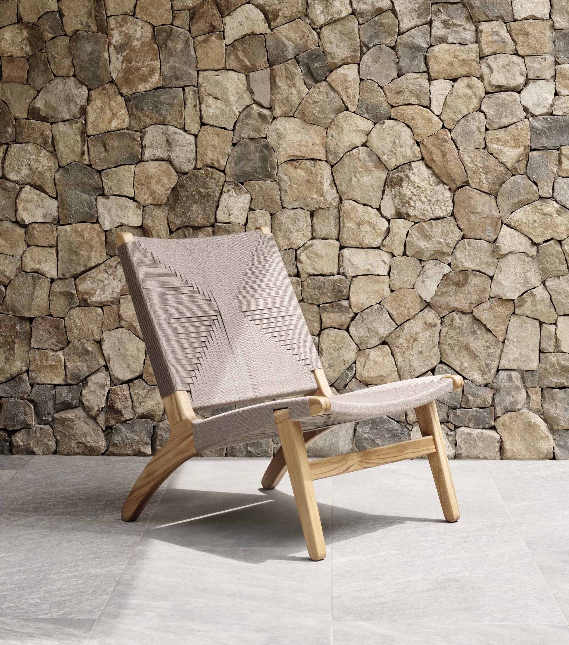 Artisan woven lounge chair styled beside a large window in a calm living room 