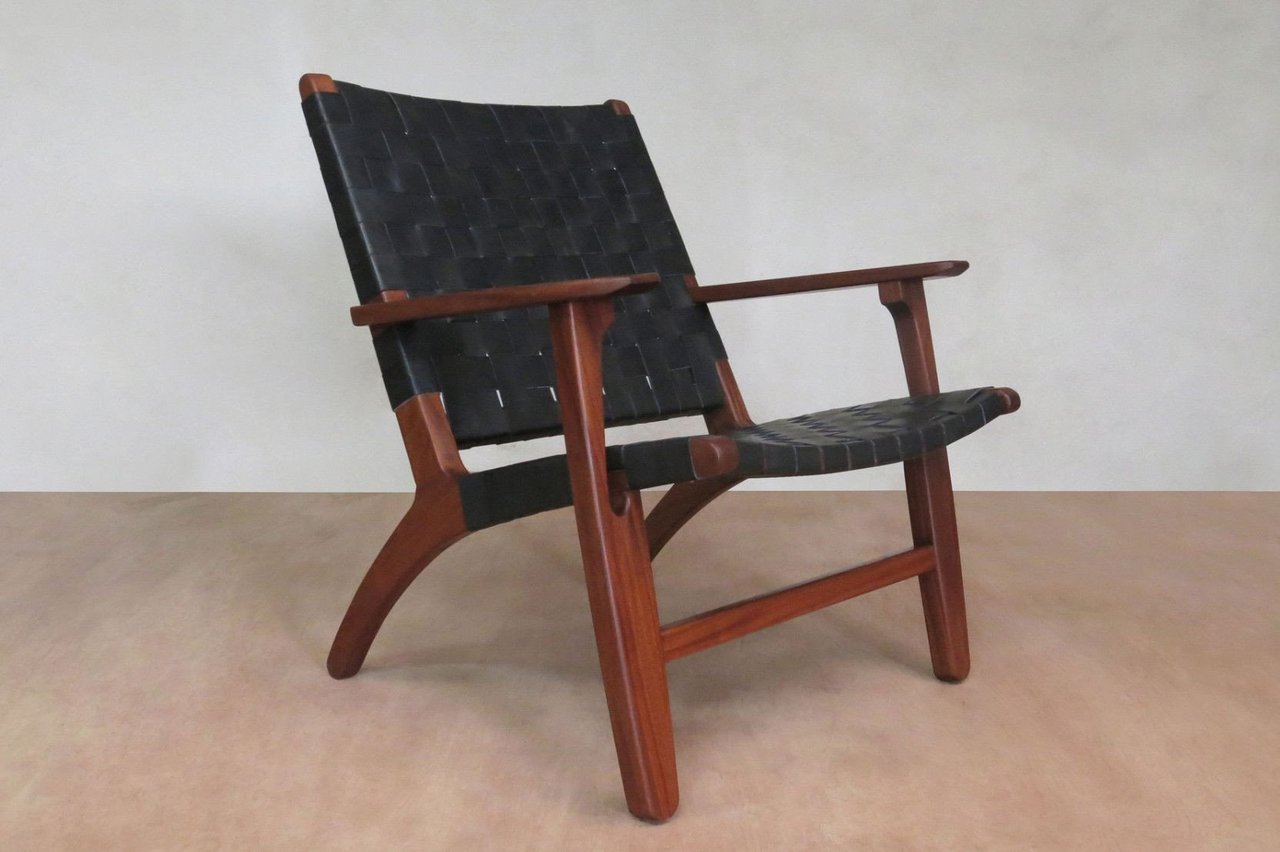 Black woven leather lounge chair with solid wood frame and handcrafted detail 