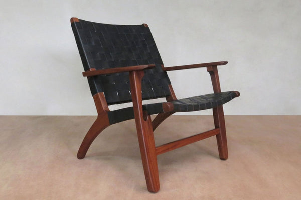 Black woven leather lounge chair with solid wood frame and handcrafted detail 