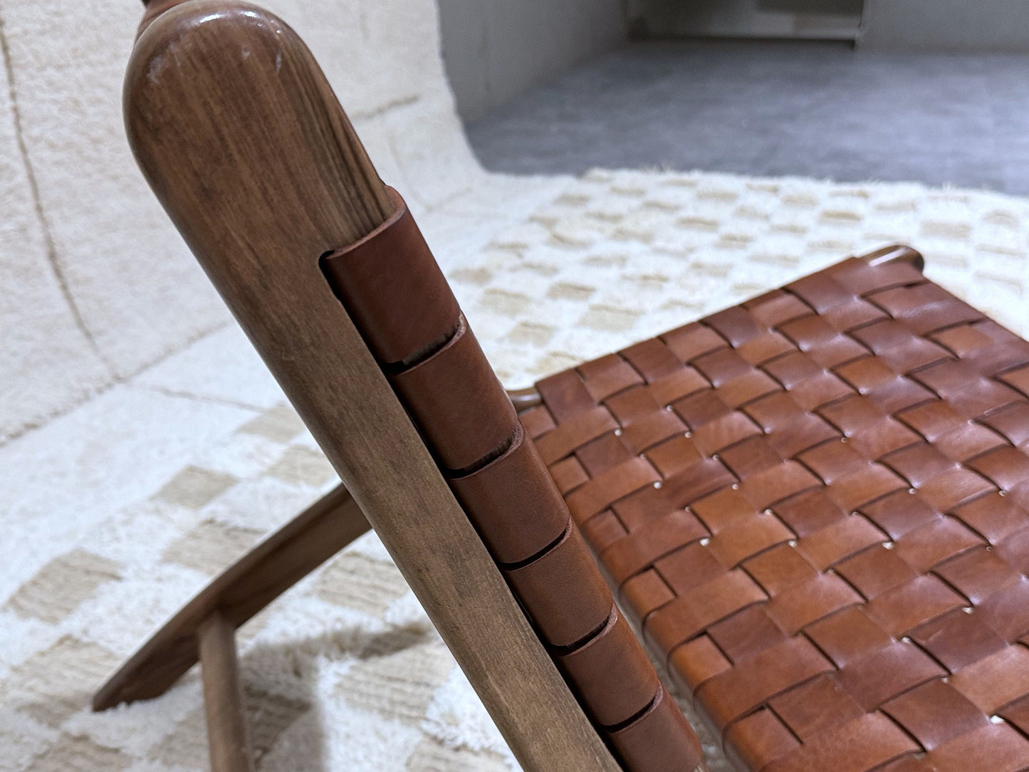 Close-up of woven brown leather seat with solid wood frame