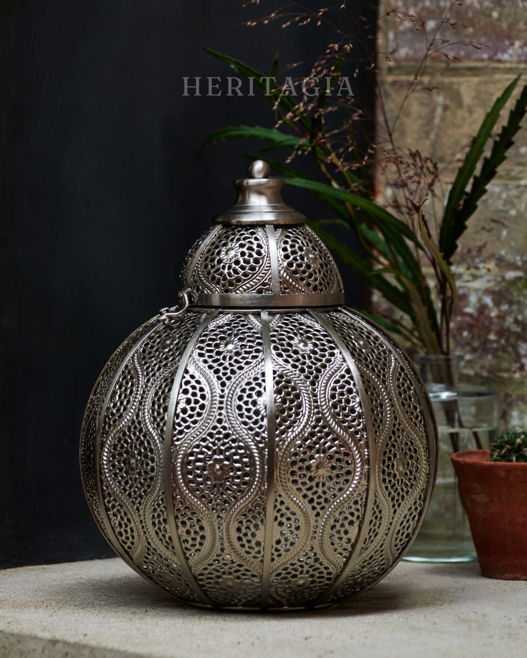 Brushed chrome Moroccan table lamp with intricate filigree pattern and warm glow 