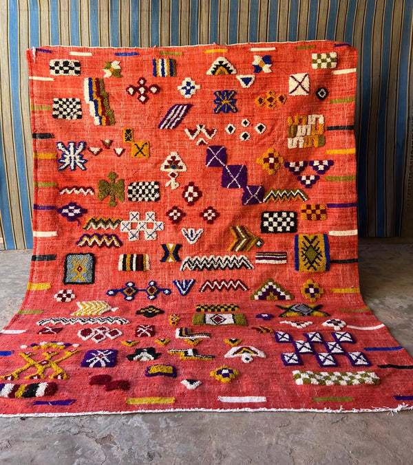 Colorful geometric Moroccan rug with red base and embroidered tribal motifs
