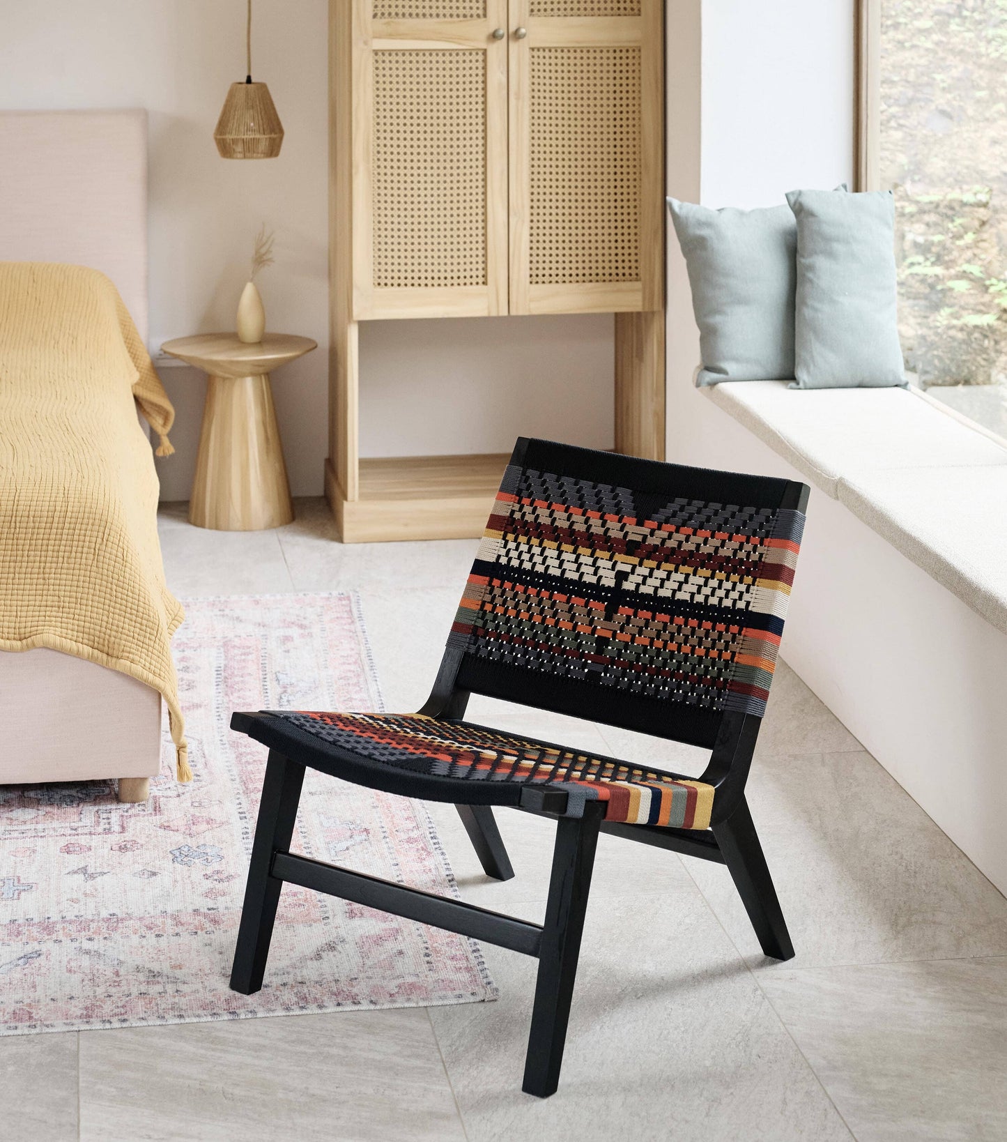 Colorful woven lounge chair with black wood frame and handmade strap detail 