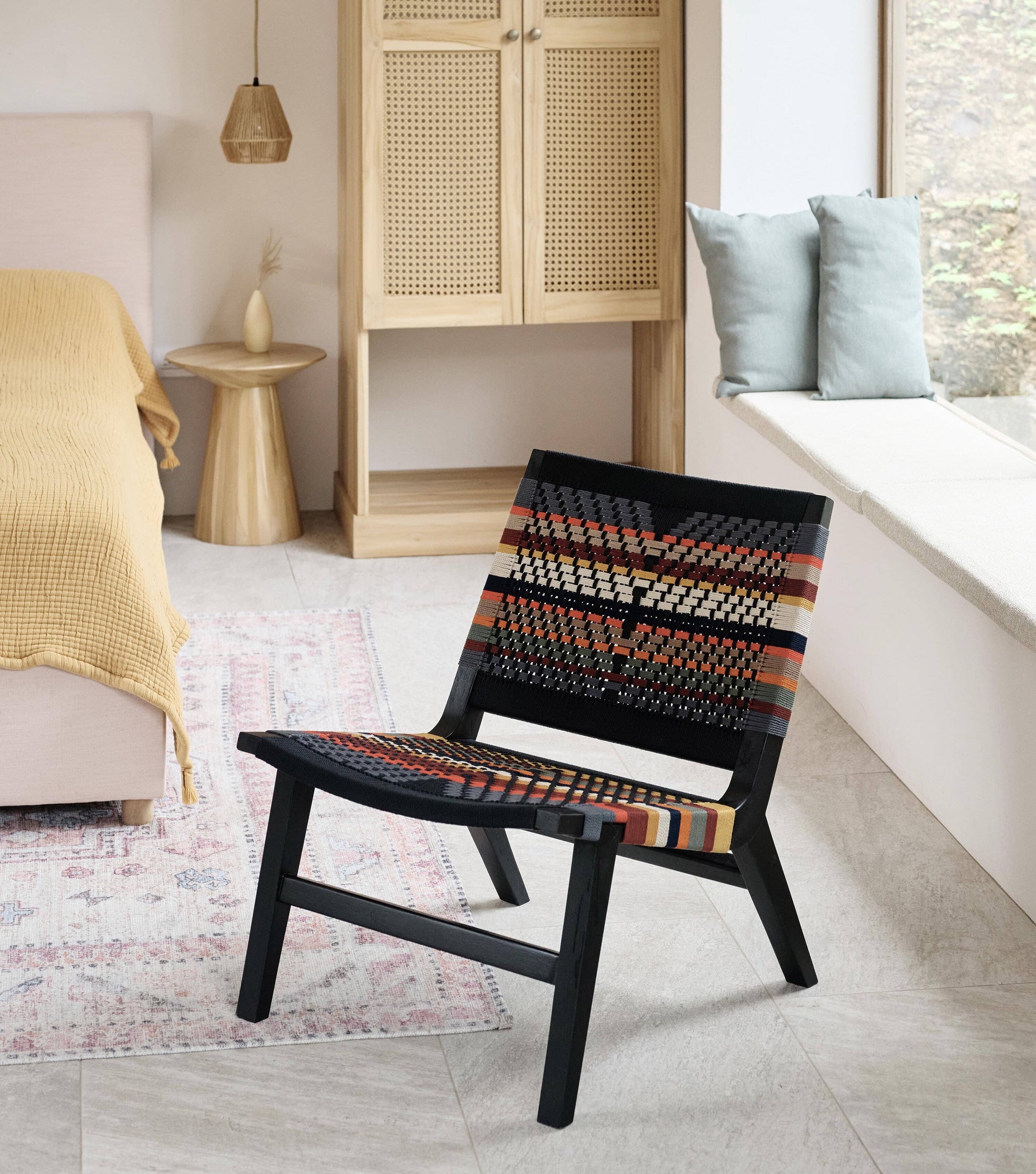 Colorful woven lounge chair with black wood frame and handmade strap detail 