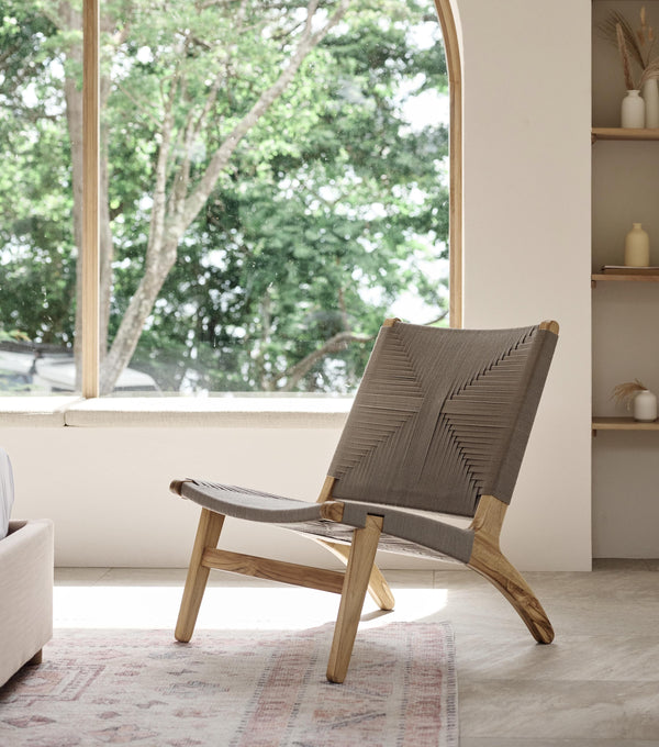 Handwoven cord lounge chair with natural wood frame in a bright relaxed interior 
