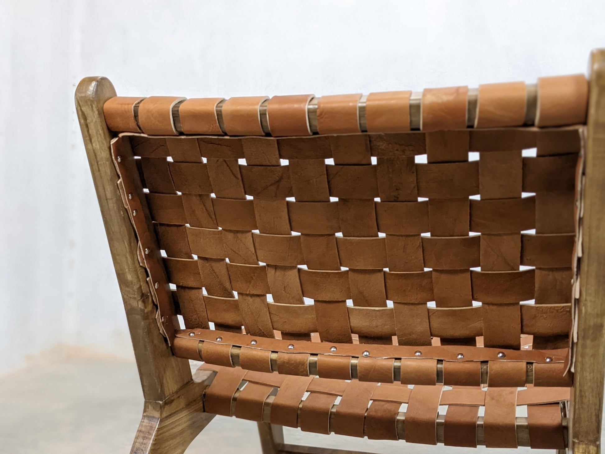 Wooden frame lounge chair featuring brown leather straps and artisan craftsmanship
